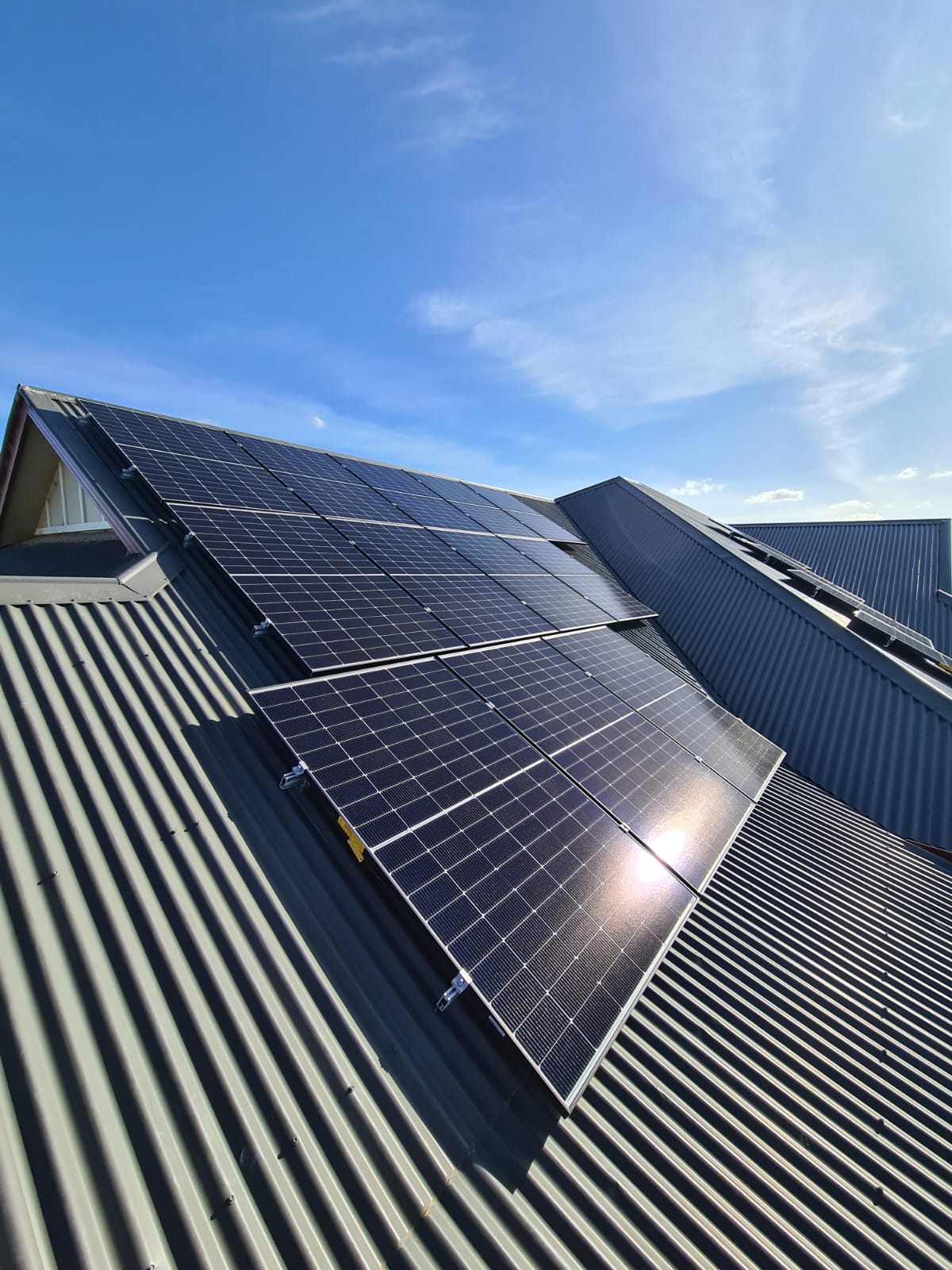 Solar panels on a corrugated metal roof under a blue sky
